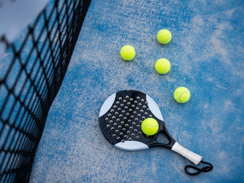 raqueta de pádel tenis junto a pelotas